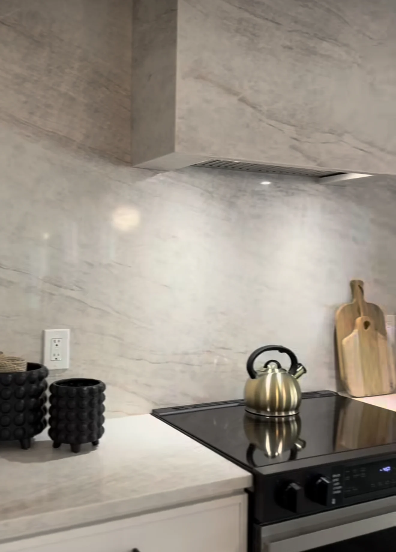 Detailed view of the stone range hood and full-height kitchen backsplash